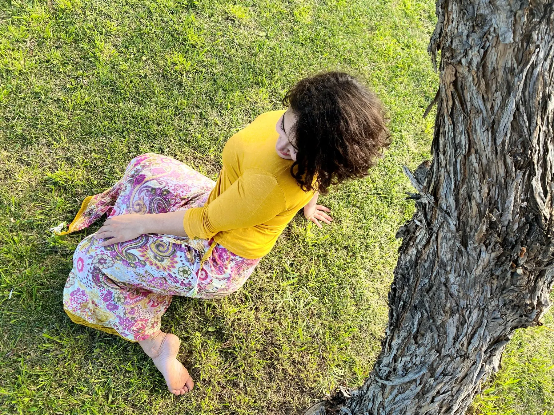 Vale Pugni sentada en el pasto junto a un árbol